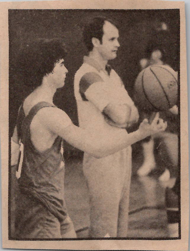 Coach holding basketball with player nearby